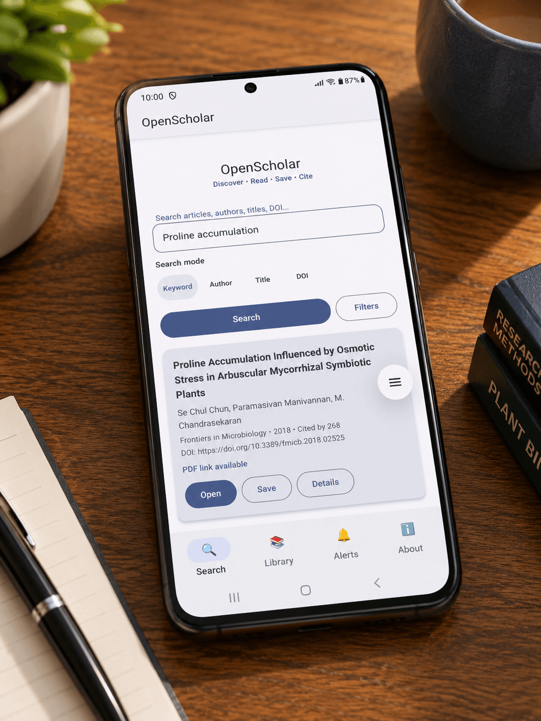 OpenScholar mobile app shown on a smartphone in a research workspace